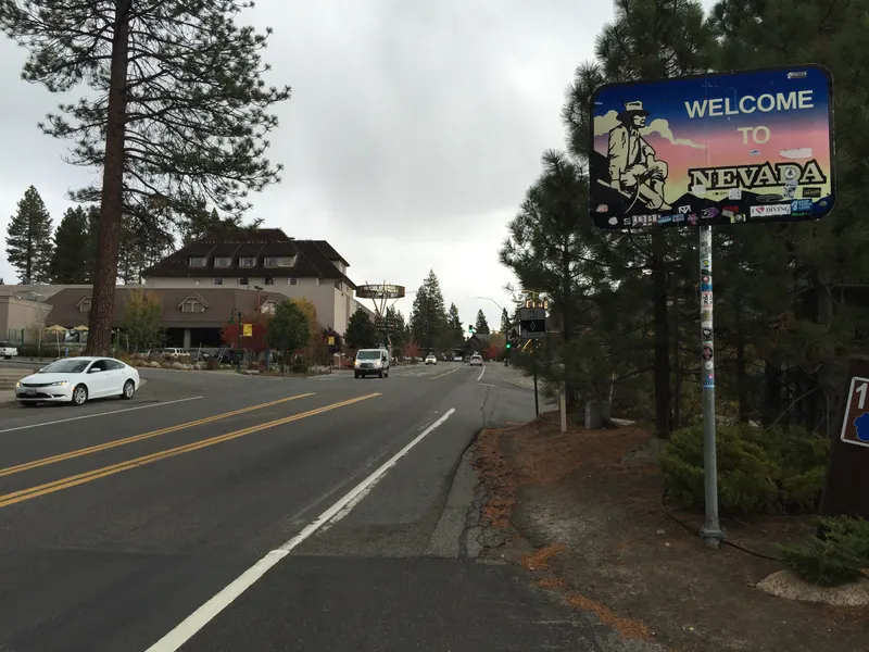 The Welcome to Nevada sign on State Route 28 at the Crystal Bay state line, with the road and buildings of Crystal Bay behind it.