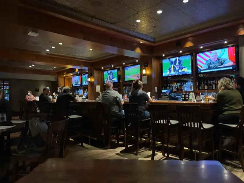 The bar and dining room at Cutthroat's Saloon in the Hyatt Regency Lake Tahoe, with dark wood tables, a long bar and TV screens.