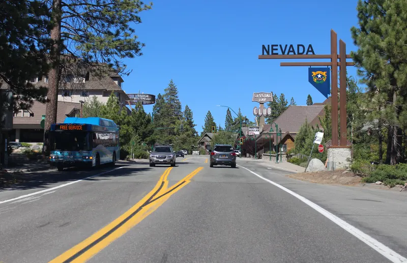 A bus on Nevada State Route 28 at the state line in Crystal Bay, with the Nevada sign over the road.
