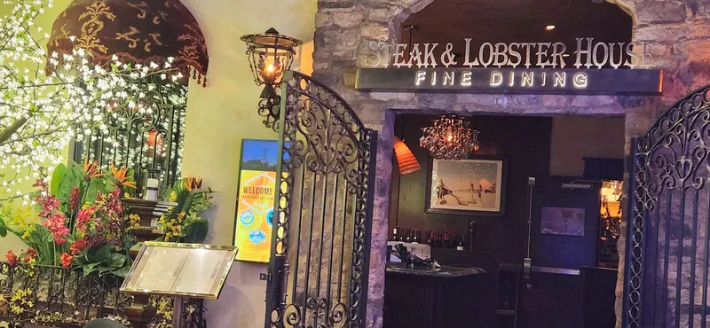 A wrought iron gate and a Steak and Lobster Fine Dining sign at the entrance.