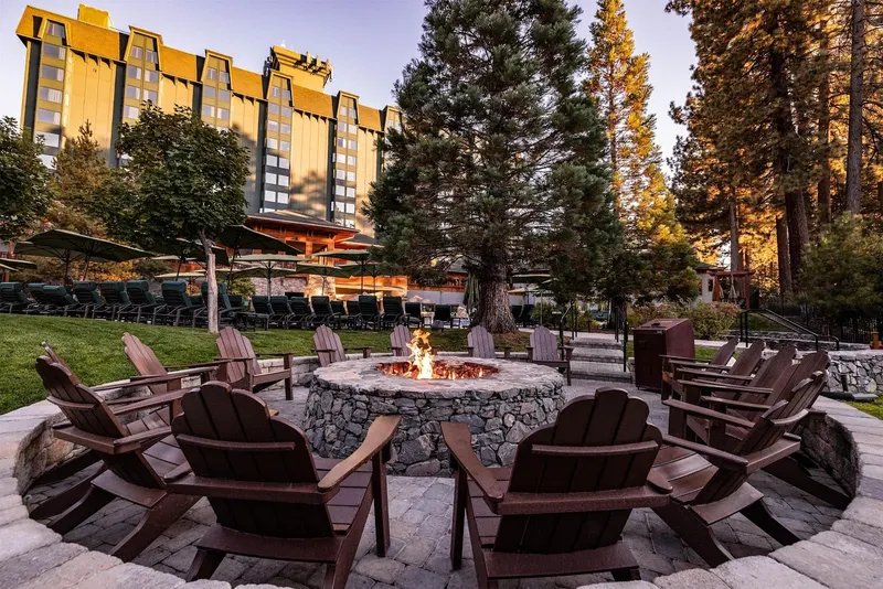 Adirondack chairs around a fire pit at dusk, with the hotel behind.