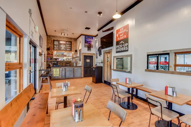 The dining room of Inclined Burgers and Brews, with wooden tables and a pickup counter.