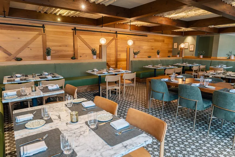 The Osteria Sierra dining room with green banquettes, tile floor and set tables.