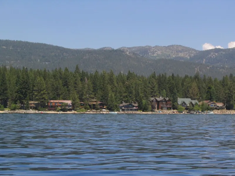 Forested hills and lakeside homes along the Incline Village shore, seen from the blue water of Lake Tahoe.