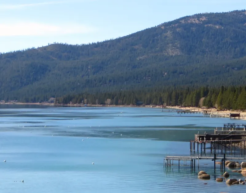 The north shore of Lake Tahoe with piers and boathouses along the water and forested hills above.