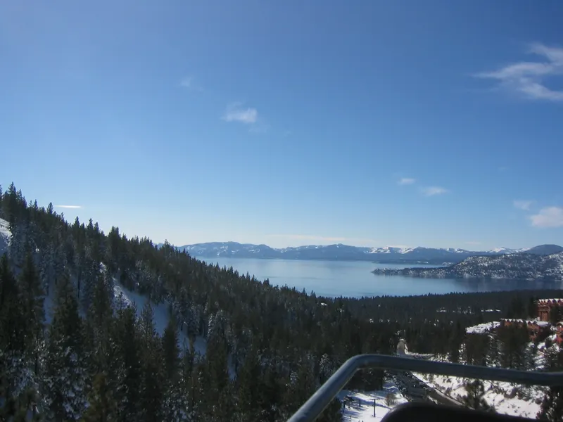 Lake Tahoe seen from a Diamond Peak chairlift on a clear winter day, with snow on the pine trees.
