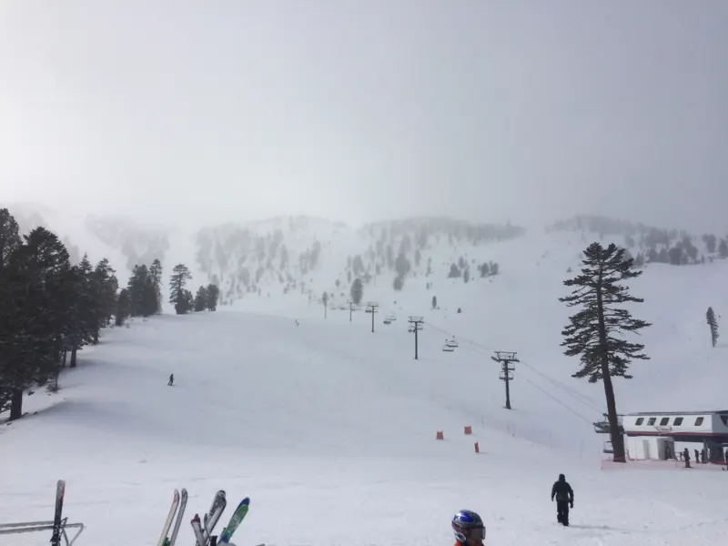 Skiers at the base of the Blazing Zephyr chairlift in falling snow at Mt. Rose.