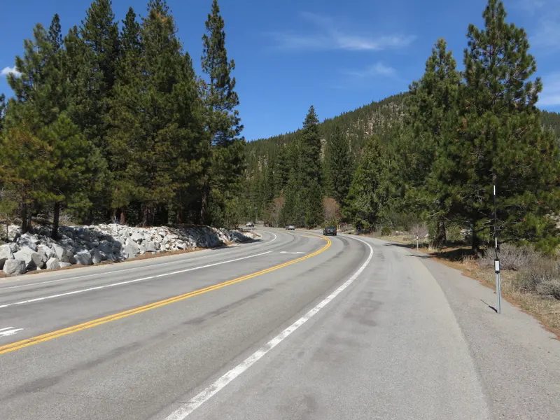 Nevada State Route 28 bending through tall pines near Incline Village, with granite rocks along the shoulder.