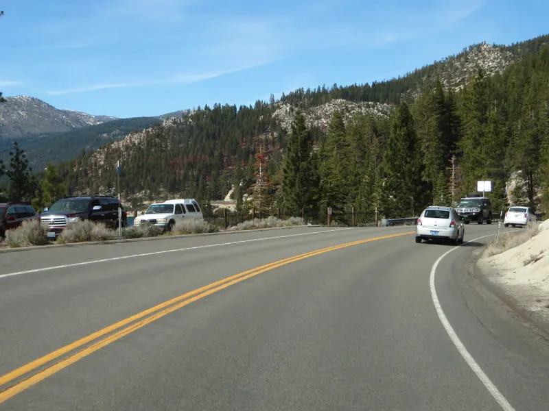 Nevada State Route 28 with parked cars beside the road and forested hills above, near Incline Village.