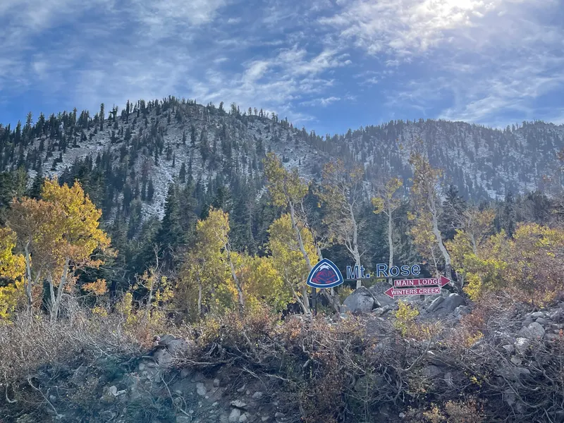 The Mt. Rose ski resort entrance sign, with Main Lodge and Winters Creek arrows, among golden aspens on Highway 431 with a rocky mountainside behind.