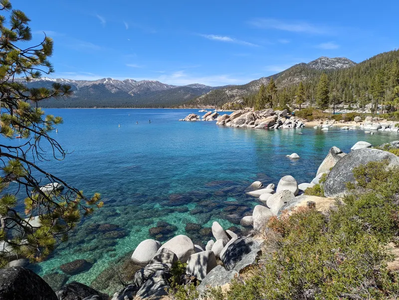 Clear blue water and pale boulders at Sand Harbor, with snowy mountains across the lake.