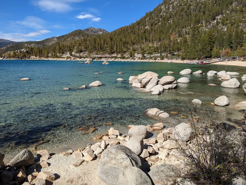 A wide cove at Sand Harbor with turquoise water, scattered boulders and a forested shore.