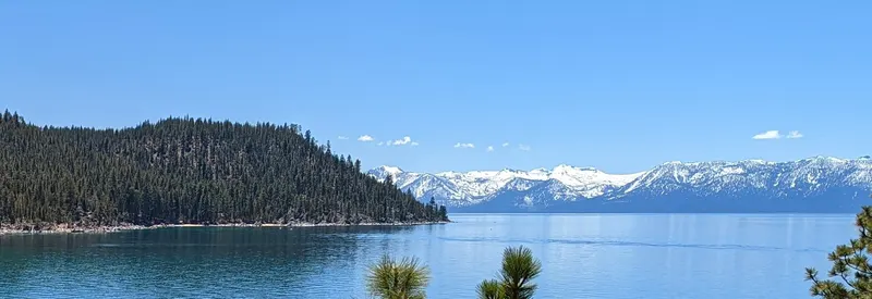 Blue water off Secret Cove with a forested headland and snowy mountains across the lake (cropped to the water and hills).