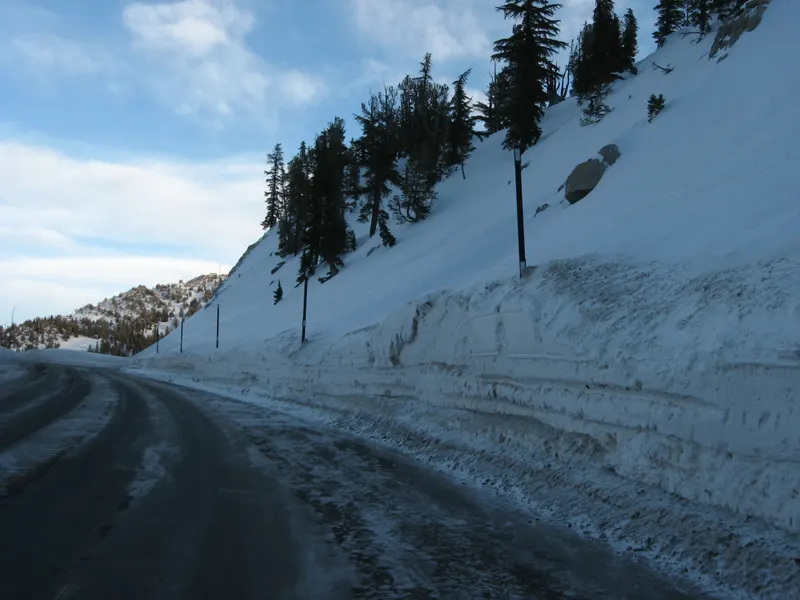 Highway 431 below Mt. Rose with a tall wall of plowed snow beside the road and a blue sky.