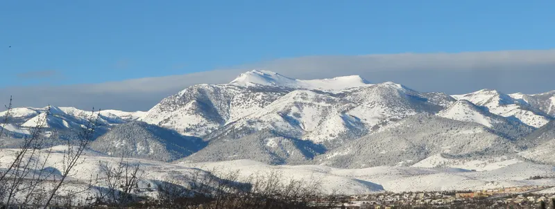 The snowy Mt Rose range glowing at sunrise with clouds drifting above the peaks.